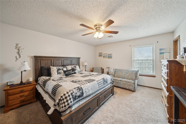 bedroom with visible vents, a ceiling fan, a textured ceiling, baseboards, and light colored carpet