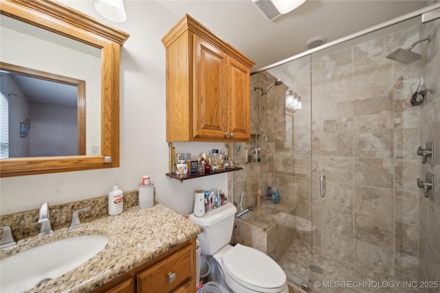 bathroom with a shower stall, toilet, and vanity