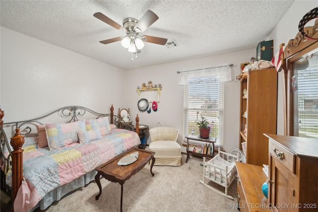 bedroom featuring a textured ceiling, light colored carpet, visible vents, and ceiling fan