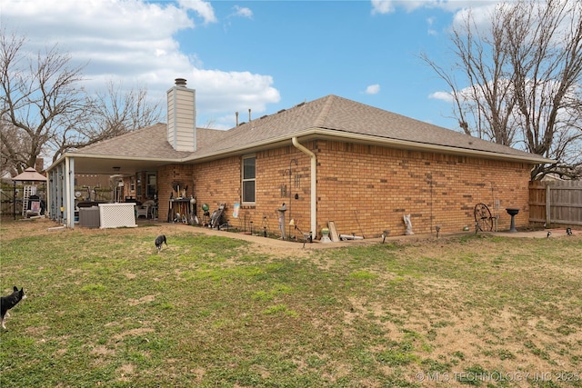 back of house featuring brick siding, fence, a chimney, a yard, and a patio