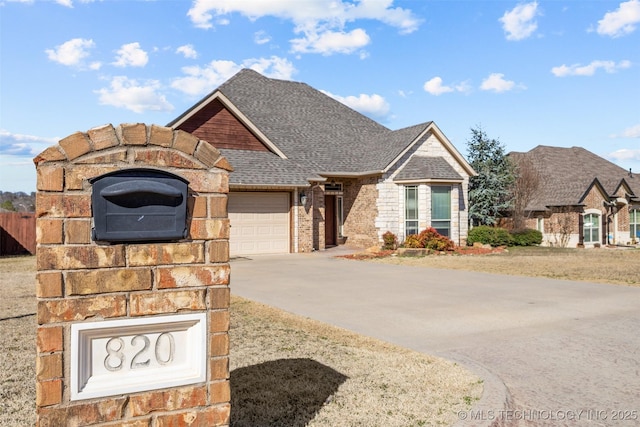 view of front facade featuring an attached garage, a shingled roof, concrete driveway, and brick siding