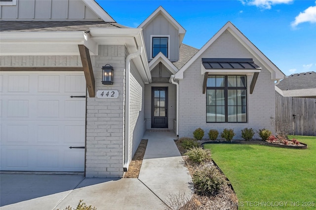 entrance to property with a garage, brick siding, fence, a yard, and board and batten siding