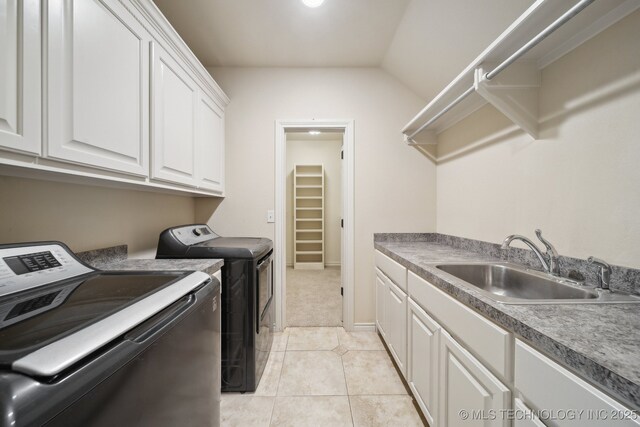 washroom with cabinet space, a sink, washing machine and clothes dryer, and light tile patterned floors