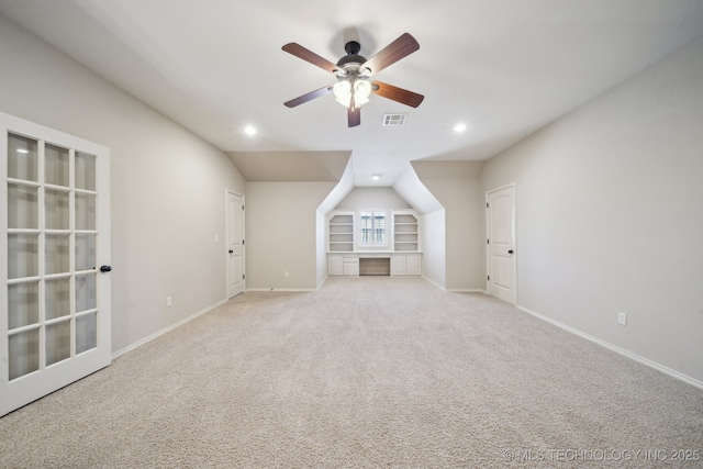 interior space featuring built in features, visible vents, a ceiling fan, light carpet, and baseboards