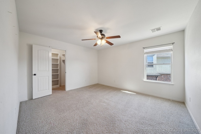 carpeted spare room with visible vents, ceiling fan, and baseboards