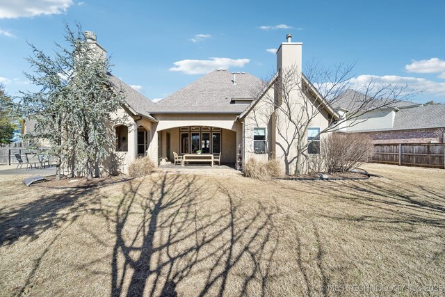 back of property with a patio, a chimney, fence, a yard, and stucco siding