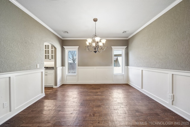 unfurnished dining area with a healthy amount of sunlight, visible vents, an inviting chandelier, and wood finished floors