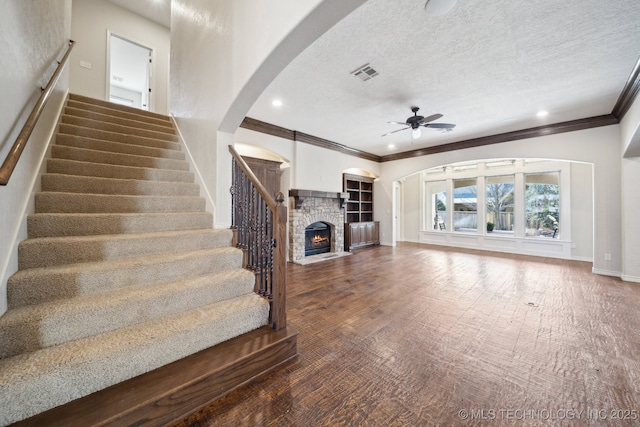 unfurnished living room with visible vents, a ceiling fan, stairs, a textured ceiling, and a fireplace