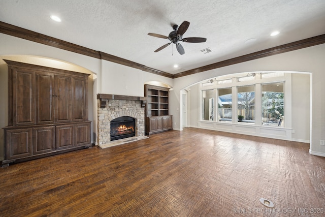 unfurnished living room with a textured ceiling, ceiling fan, a fireplace, wood finished floors, and baseboards