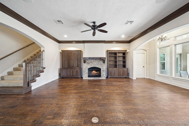 unfurnished living room with a textured ceiling, a stone fireplace, wood finished floors, and visible vents