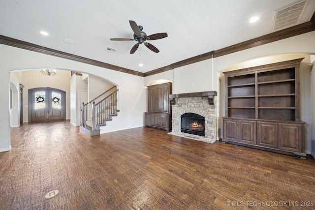 unfurnished living room featuring dark wood-style floors, arched walkways, visible vents, and baseboards