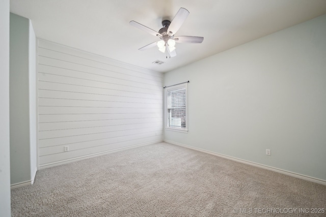 carpeted empty room with visible vents, ceiling fan, and baseboards