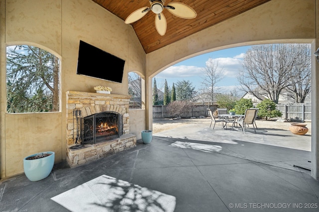 view of patio / terrace with a fenced backyard, an outdoor stone fireplace, outdoor dining area, and a ceiling fan