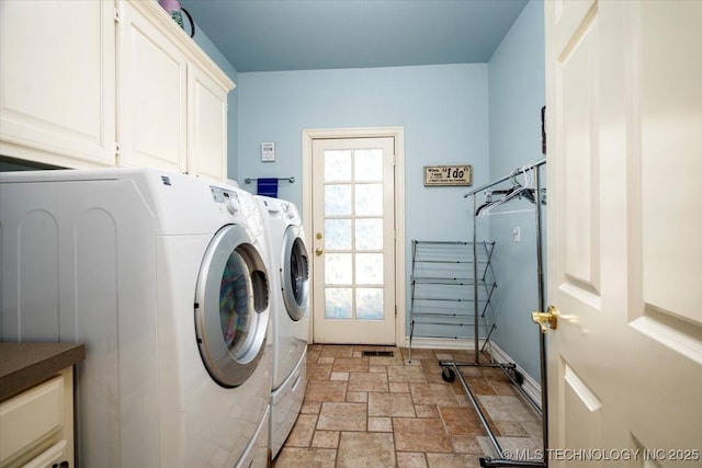 laundry area with cabinet space, washing machine and dryer, stone finish floor, and a wealth of natural light