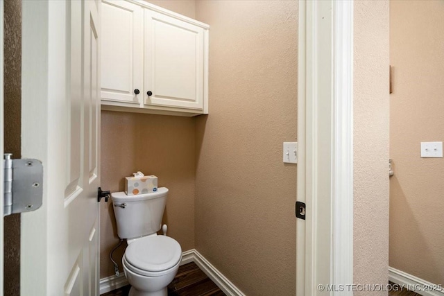 bathroom with a textured wall, wood finished floors, toilet, and baseboards