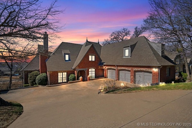 view of front facade with concrete driveway, brick siding, a chimney, and roof with shingles