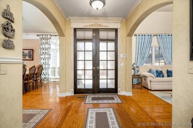 foyer entrance with ornamental molding, plenty of natural light, and wood finished floors