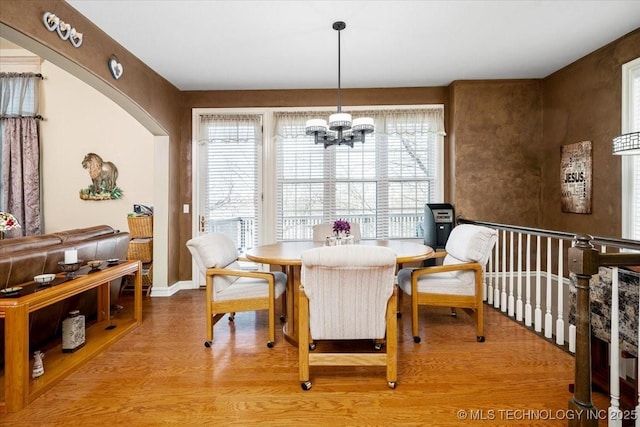 dining area with a chandelier, arched walkways, and wood finished floors