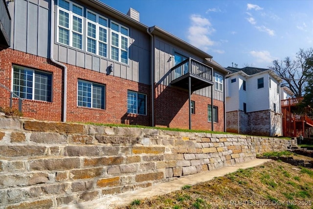 back of house featuring brick siding, board and batten siding, and a chimney