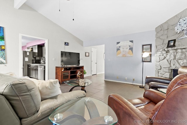 tiled living area featuring baseboards, a sink, ceiling fan, a fireplace, and high vaulted ceiling