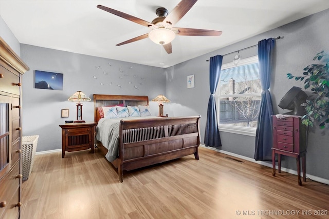 bedroom featuring visible vents, baseboards, a ceiling fan, and wood finished floors