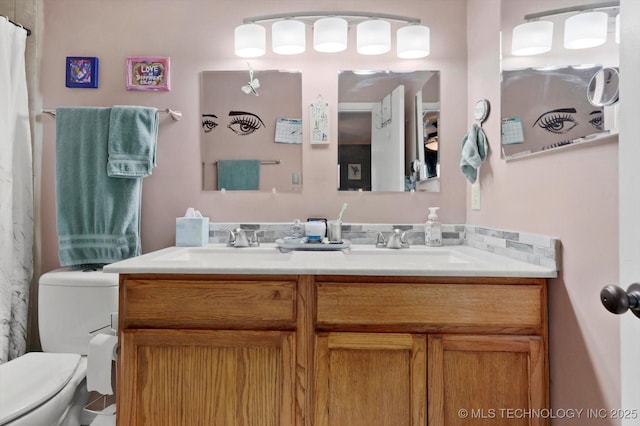 bathroom featuring a sink, double vanity, and toilet