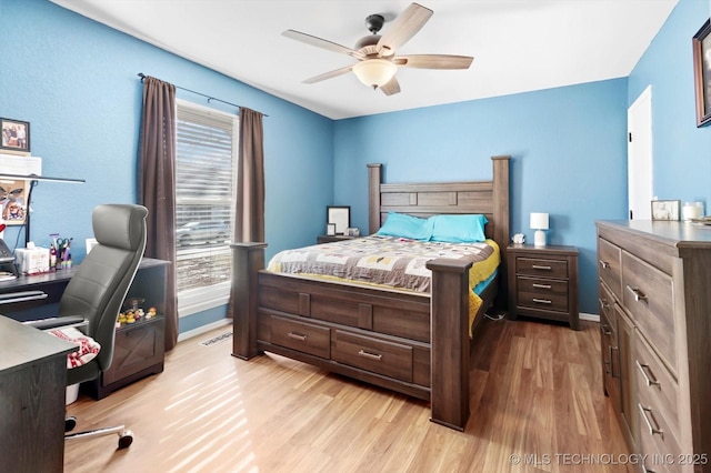 bedroom featuring ceiling fan, multiple windows, baseboards, and wood finished floors
