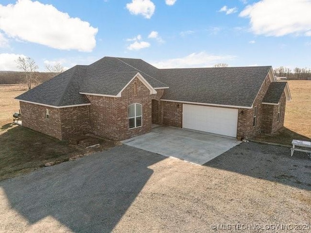 ranch-style house featuring a shingled roof, concrete driveway, brick siding, and an attached garage