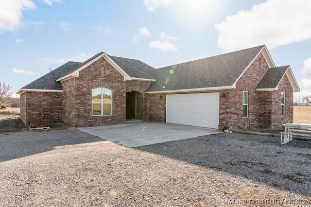 single story home with an attached garage, a shingled roof, concrete driveway, and brick siding