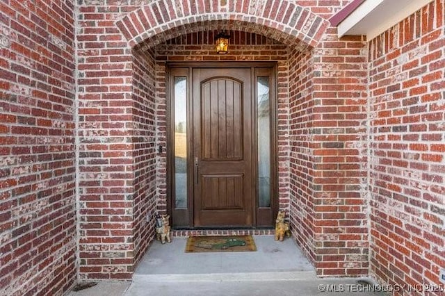 view of exterior entry featuring brick siding