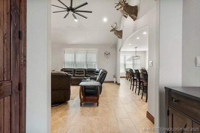 living room featuring arched walkways, light tile patterned flooring, baseboards, and recessed lighting