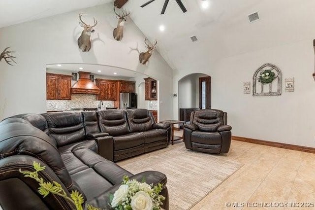 living room featuring arched walkways, high vaulted ceiling, ceiling fan, visible vents, and baseboards