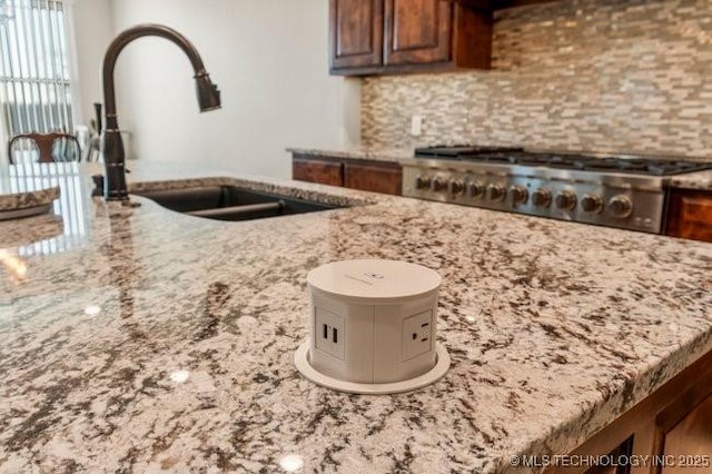 kitchen with tasteful backsplash, light stone counters, and range