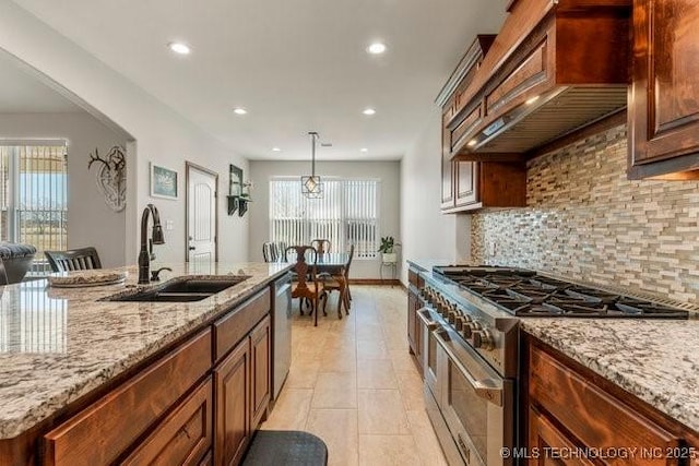 kitchen featuring tasteful backsplash, custom range hood, appliances with stainless steel finishes, a sink, and light stone countertops