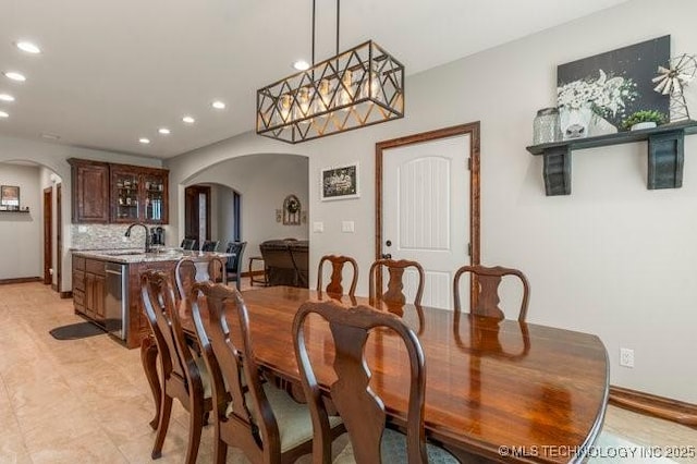 dining room featuring arched walkways, baseboards, and recessed lighting