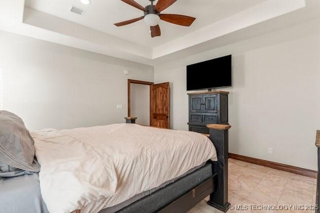 bedroom with baseboards, visible vents, a tray ceiling, and ceiling fan