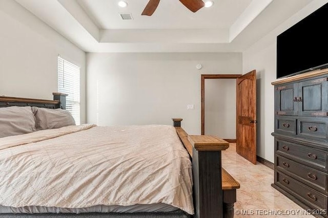 bedroom with a raised ceiling, visible vents, and ceiling fan