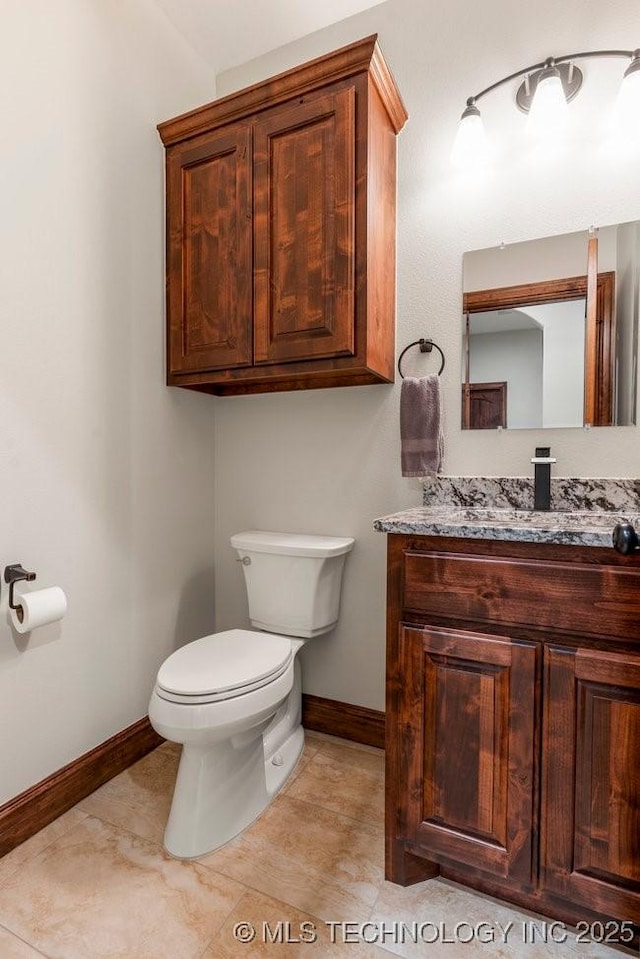 bathroom with tile patterned flooring, vanity, toilet, and baseboards