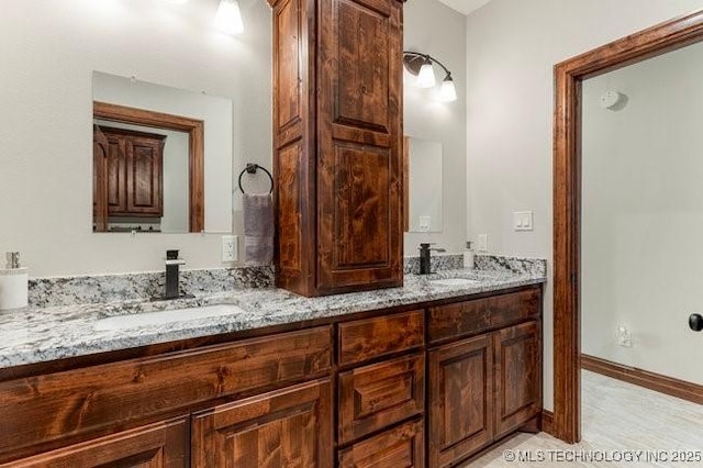 full bathroom with a sink, baseboards, and double vanity