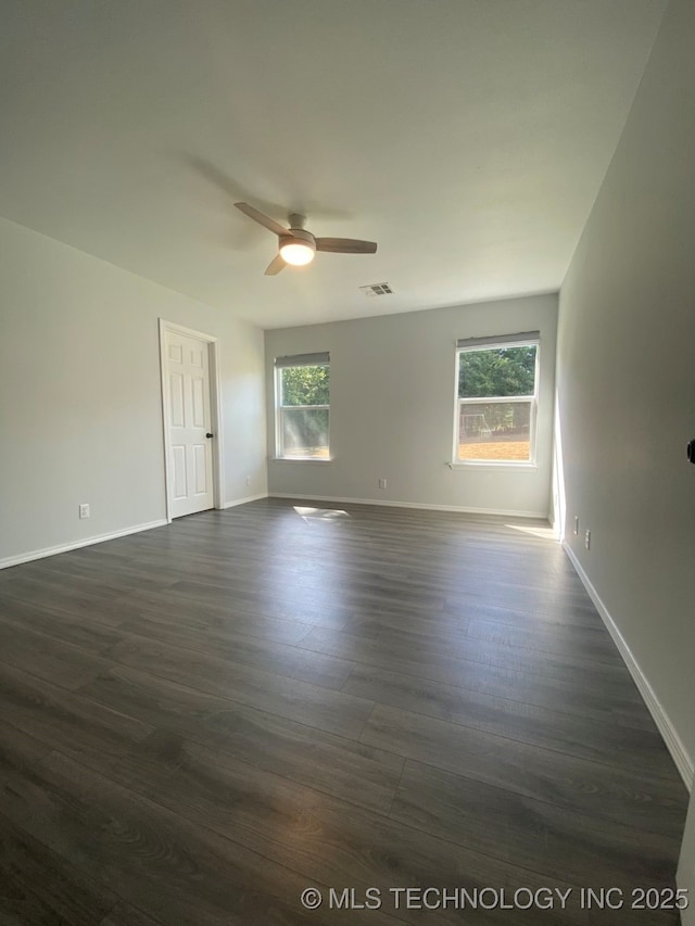 spare room featuring ceiling fan, baseboards, visible vents, and dark wood finished floors