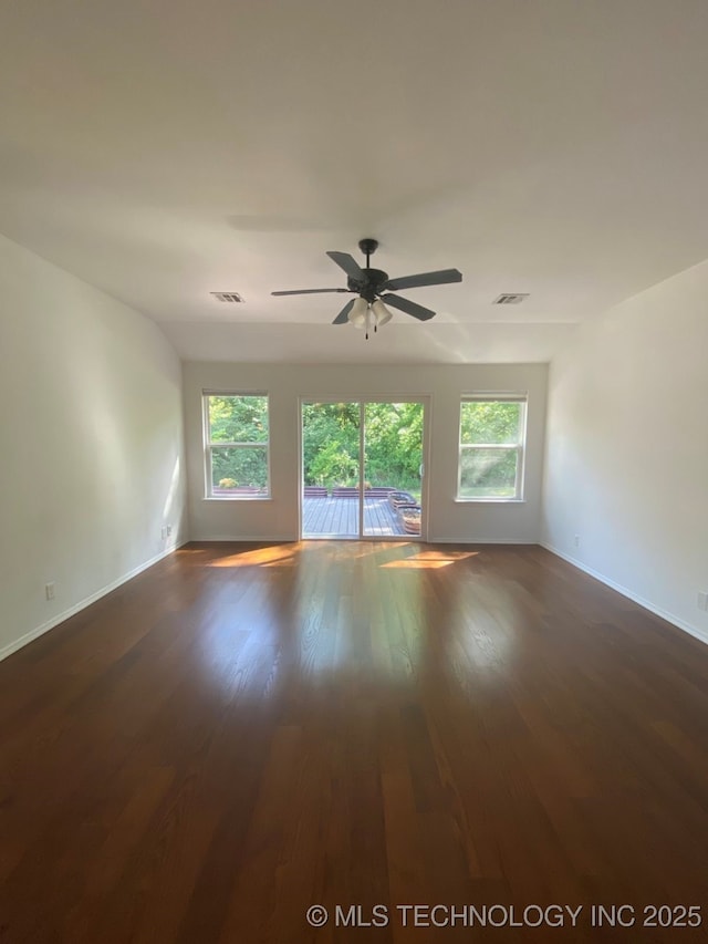 unfurnished room featuring dark wood-style floors, visible vents, plenty of natural light, and ceiling fan