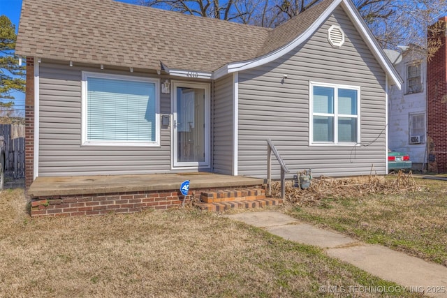 view of front of property with a shingled roof and a front yard