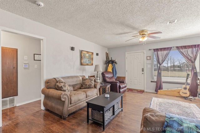 living area featuring a ceiling fan, visible vents, and wood finished floors