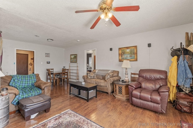 living room featuring ceiling fan, a textured ceiling, and wood finished floors