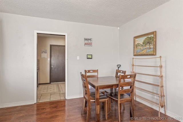 dining space featuring a textured ceiling, baseboards, and wood finished floors