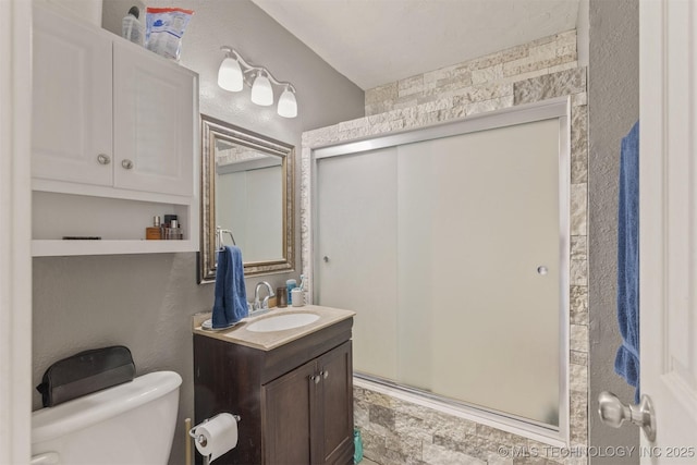 bathroom featuring a textured wall, a stall shower, vanity, and toilet