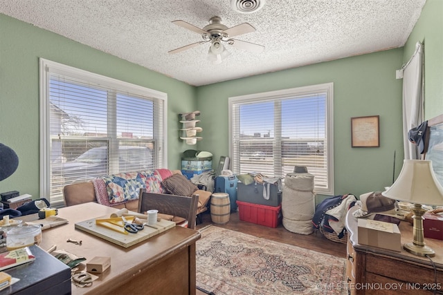 interior space with visible vents, ceiling fan, a textured ceiling, and wood finished floors