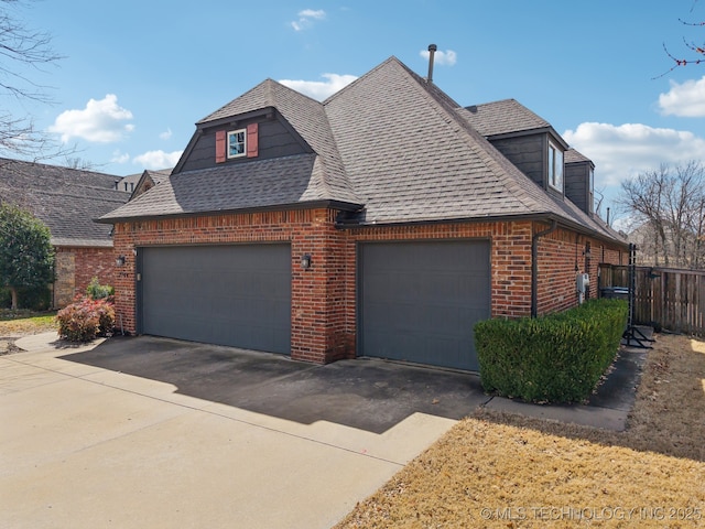 view of front of home with a garage, driveway, a shingled roof, fence, and brick siding