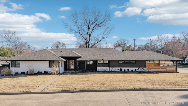 view of front facade featuring a chimney, a front lawn, and roof with shingles