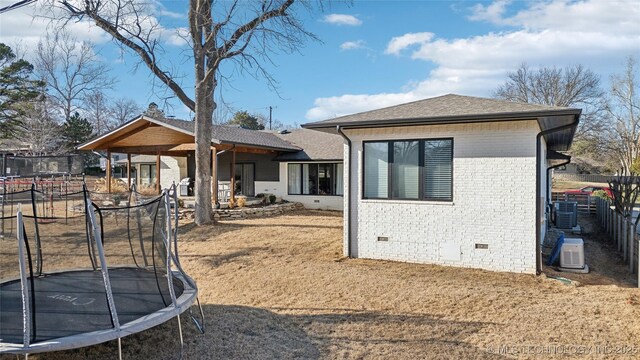 2808 E 37th Pl, Tulsa, OK 74105 - back of property with a trampoline, crawl space, brick siding, and a shingled roof
